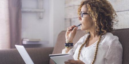 Woman thinking about why she can't decorate while chewing on her pen and staring out the window